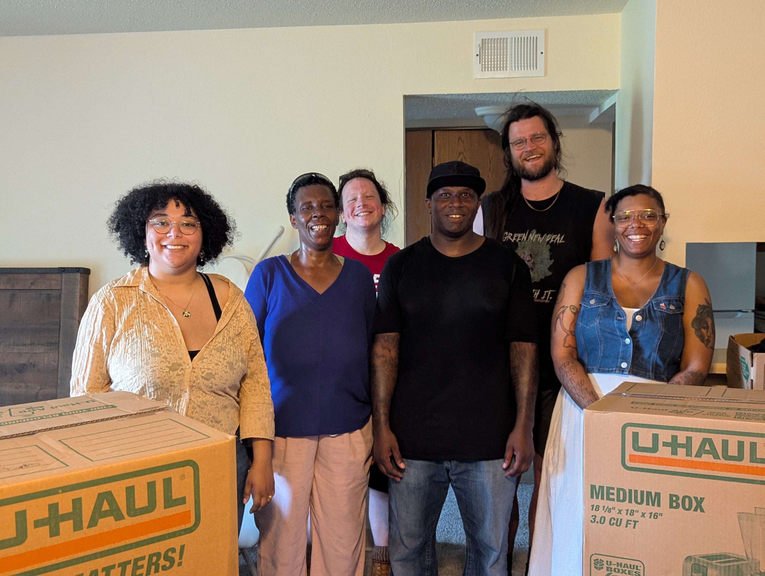 Tenant union members and former Sycamore Townhomes residents smiling behind U-haul boxes.